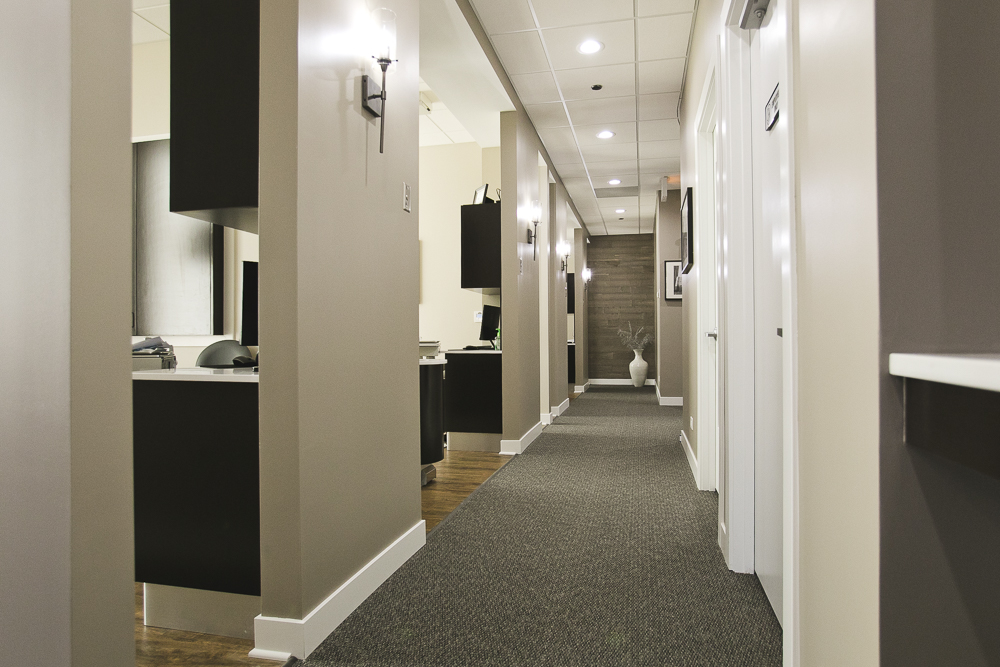 A hallway at a dental office with a row of patient rooms, all with clean, fresh and modern furnishings